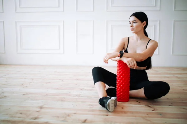 Örnek kız sporcu antrenman için kırmızı masaj rulosunu gösteriyor. — Stok fotoğraf