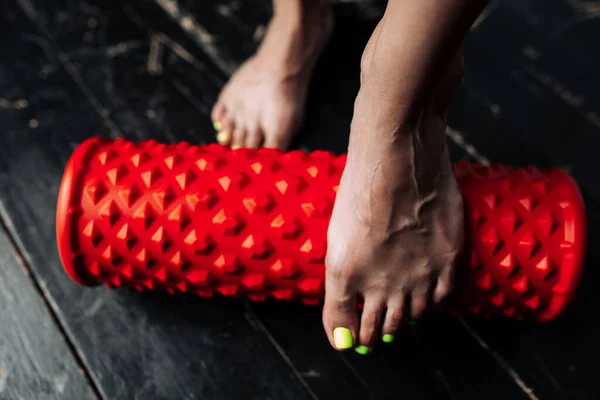 Primer plano de la pierna femenina desnuda con rollo de masaje rojo para el entrenamiento — Foto de Stock