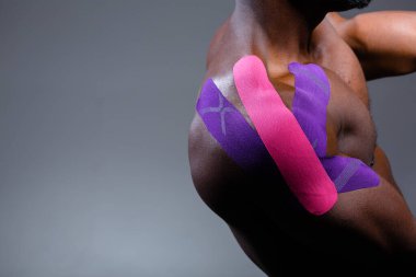 Close-up of an African American shoulder. Kinesio tape on the shoulder joint clipart