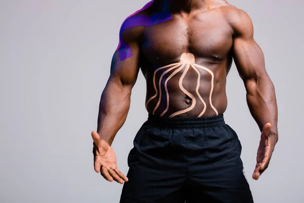 Torso afroamericano muscular. Cinta de cinesioterapia pegada a los músculos abdominales —  Fotos de Stock
