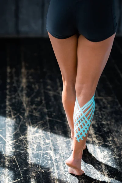 Women\'s legs with kinesio tape on the calf muscle. back view