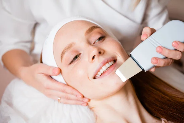 Retrato de una chica pelirroja con un dispositivo cosmético para la limpieza ultrasónica cerca de la cara — Foto de Stock