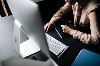 Yukarıdan bak. Kız ofis çalışanı bilgisayarda oturup grafik tableti üzerinde çalışıyor.