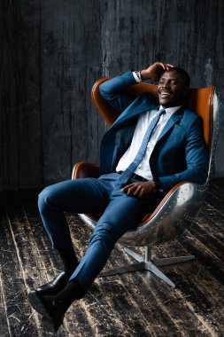 Mavi takım elbiseli Afro-Amerikan bir ofis çalışanı çatı katında dinleniyor.