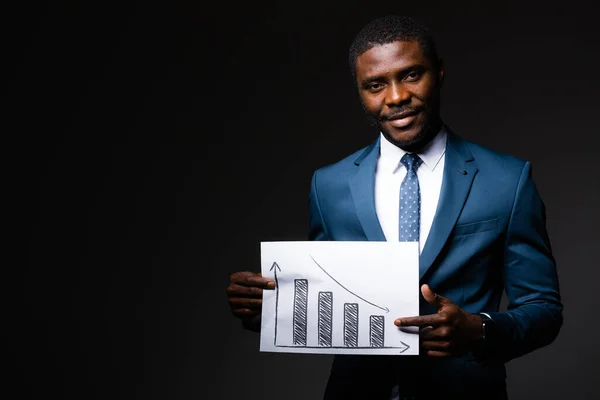 Africký americký muž manažer drží graf klesajících prodejů v důsledku koronavirové infekce — Stock fotografie