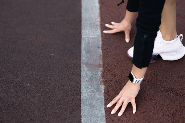 Primer plano de las manos de una atleta. Chica se encuentra en un comienzo bajo en una cinta de correr — Foto de Stock