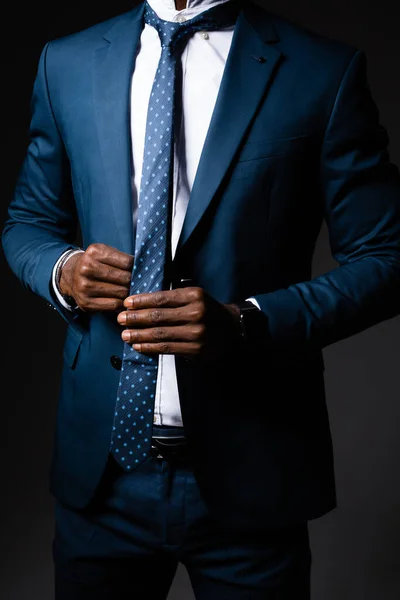 Чоловік у діловому костюмі вирівнює краватку навколо шиї — стокове фото