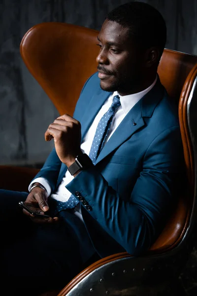Θέα από ψηλά. Επιχειρηματίας αφροαμερικανός κάθεται σε μια σοφίτα πολυθρόνα με ένα τηλέφωνο στα χέρια του — Φωτογραφία Αρχείου