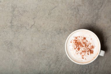Gri arka planda tarçınlı bir fincan kapuçino kahvesi. Metin için boşluk