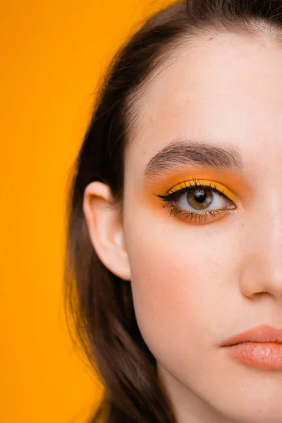 Retrato de media cara de una chica atractiva con maquillaje amarillo brillante. Modelo se levanta sobre un fondo amarillo —  Fotos de Stock