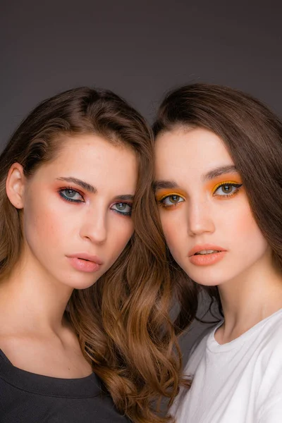 Dos hermosas modelos femeninas con maquillaje de abanico sobre un fondo gris —  Fotos de Stock