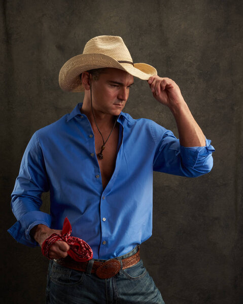 The sexy cowboy wears a blue shirt.