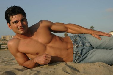 the handsome man poses in the beach. clipart