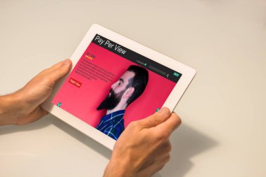 Ekranda paralı web sitesi olan bir tableti tutan adamın ellerini kapatın. Tüm ekran grafikleri uydurma