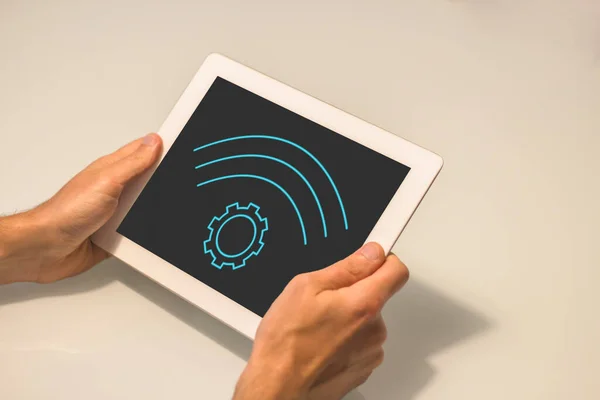 Tableti yatay pozisyonda tutan iki el. Aygıtın siyah bir ekranı ve arka planı beyaz.