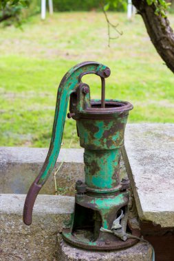Çiftlikteki bir kuyudan su çekmek için eski bir metal pompa.