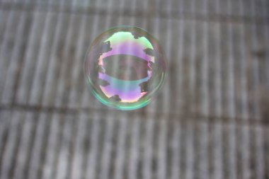 Açık havada bir sabun köpüğünün yakın görüntüsü. Arkaplanda döşeme döşemesi