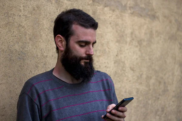 Young Man Beard Checking Smartphone Wall House Background — Stock Photo, Image