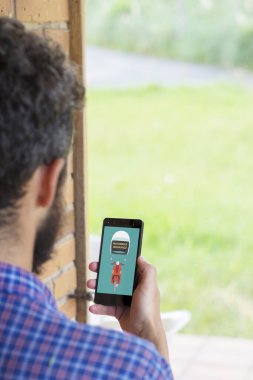 Arka planda, ekranda motosiklet sigortası konsepti olan akıllı telefonu tutan genç bir adam var. Tüm grafikler uydurmadır..