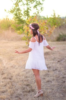 Hippi yaz konsepti. Kafasında çiçek kolyesi olan güzel genç bir kadın parkta dans ediyor.