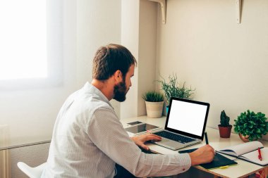 Evde dijital tablet ve laptop kullanan grafiksel tasarımcı. Tasarım için boş ekran