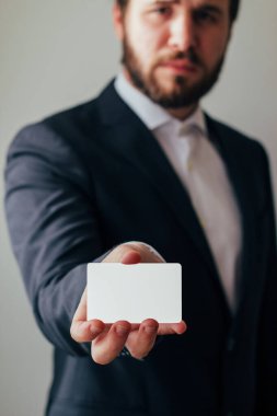 Boş beyaz kartvizit gösteren bir adamın yakın görüntüsü. Gri arkaplan