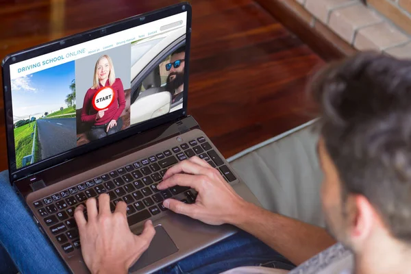 Ekranda sürücü kursunun internet sitesi olan dizüstü bilgisayarla evde oturan genç adamın yakın görüntüsü. Ev kavramından eğitim