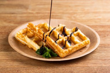 Tek kullanımlık tabakta Viyana waffle 'ı, sıvı çikolata, şeker ve nane şekeri. Aşçı tatlı olarak sıvı çikolata koyar.
