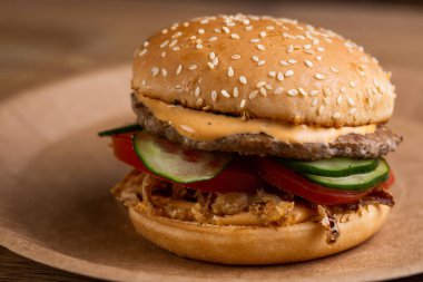 Biftek köfteli çizburger, kızarmış soğan, taze sebze ve kremalı sos.