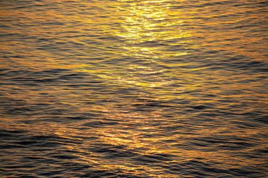 Soyut doğal arkaplan: Sabah denizin yüzeyinde yükselen güneşin altın yolu