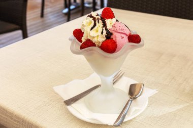 Dondurmalı vazo, çilek ve çikolata sosu bir yaz kafesinin masasında.