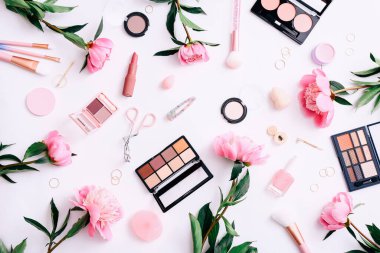 Beyaz masaüstü arka planında yüz kozmetik ürünleri ve şakayıklar olan güzellik geçmişi. Üst görünüm