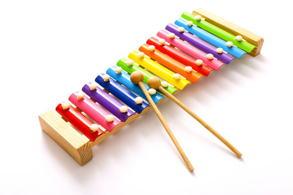 Деревянная игрушка ксилофон цвета рейнбоу с двумя палками на белом фоне.