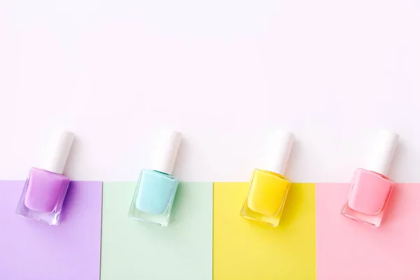 Группа лаков для ногтей разных цветов на красочном фоне. Вид сверху — стоковое фото