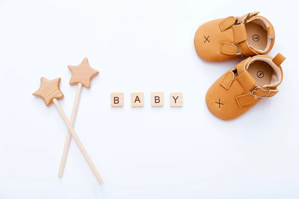 Blocchi di legno con scritta Baby, stivaletti e stelle di legno vicino su sfondo bianco. Vista dall'alto — Foto Stock