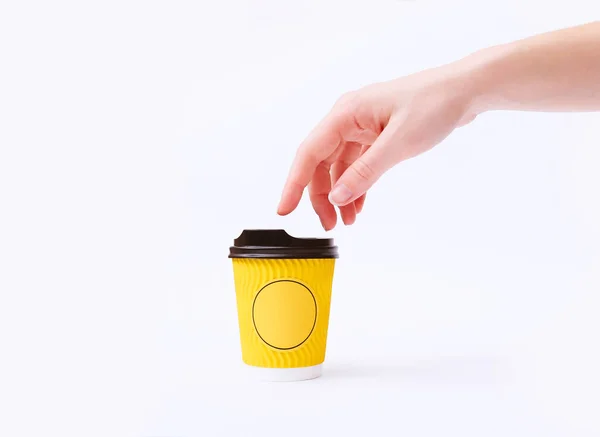 Kreativ mock upp bild av kvinna hand röra gult papper kaffekopp på vit bakgrund i minimalism stil. Mall för feminin blogg, sociala medier — Stockfoto