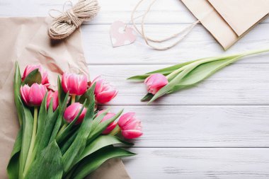 Lale buketi. Çiçekçi işyeri geçmişi. Pembe çiçekler, ahşap masaya dizilmiş aletler. Bir demet oluşturmak için hazırlık. Çiçekçilik, dekoratör, diy, işçilik, bahar hediyesi konsepti.