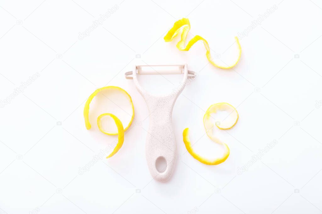 Lemon zest with zester on a white background. Top view