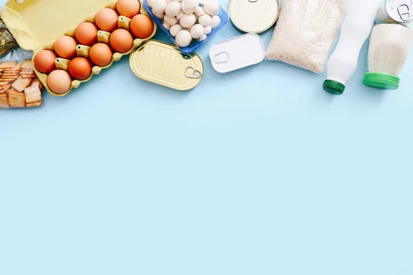 Набор продуктов питания из консервов, овощей, зерновых на синем фоне. Концепция доставки продуктов питания. Концепция пожертвований. Вид сверху. — стоковое фото