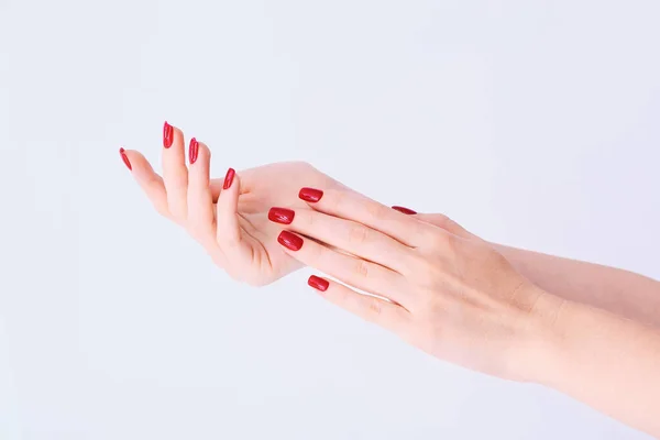 Manos de una joven con larga manicura roja en las uñas sobre fondo blanco — Foto de Stock