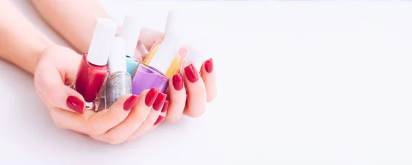 Esmalte de uñas. Manicura artística. Nail Polish Bottles multicolor en las manos. Clavos rojos con estilo — Foto de Stock