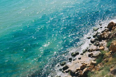 Dalgalı parlak Karadeniz. Geniş kumlu sahil, arka planda kum tepeleri ve ormanlar olan büyük taşlar.