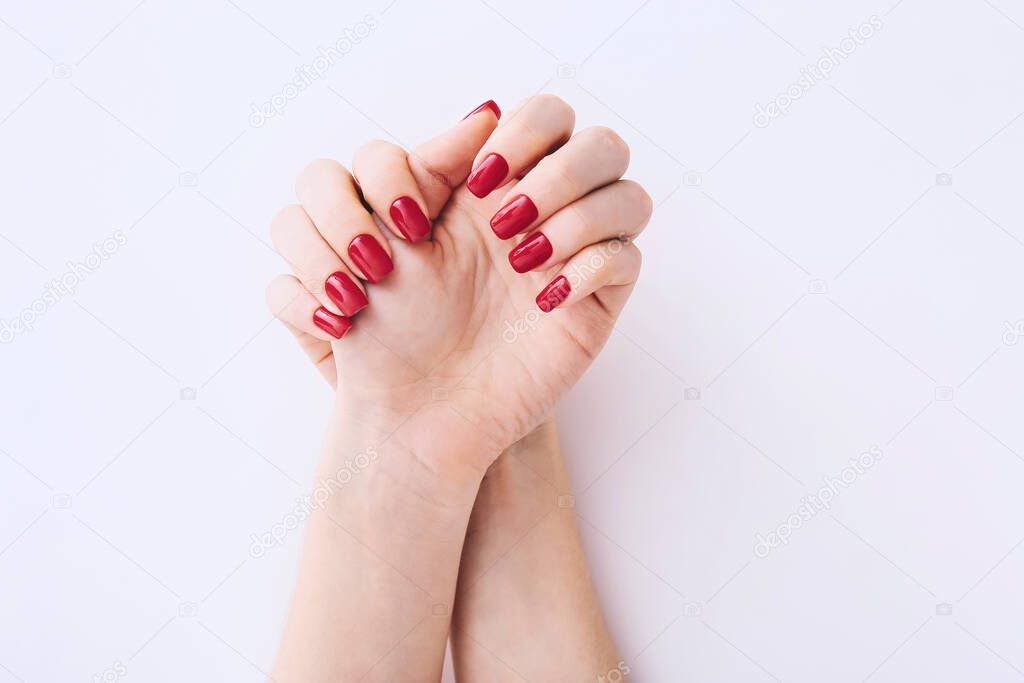 Female hands with red manicure on light grey background. Top view
