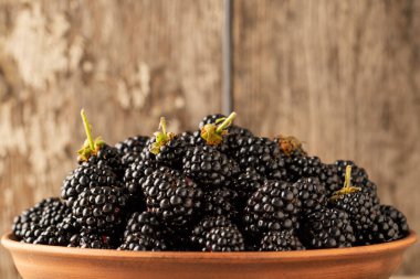 Kırsal masadaki bir kasede taze böğürtlenlerin yakın çekimi. Köy masasında taze böğürtlenler. Boşluğu Kopyala.