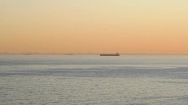 Denizde romantik, renkli bir gün batımı. Güneş batıyor, mavi ve turuncu bulutlar gökyüzünde akıyor. Muhteşem yaz manzarası. Güzellik dünyasını keşfetmek, seyahat, tatil, eğlence. Yavaş çekim süresi 4K görüntüsü