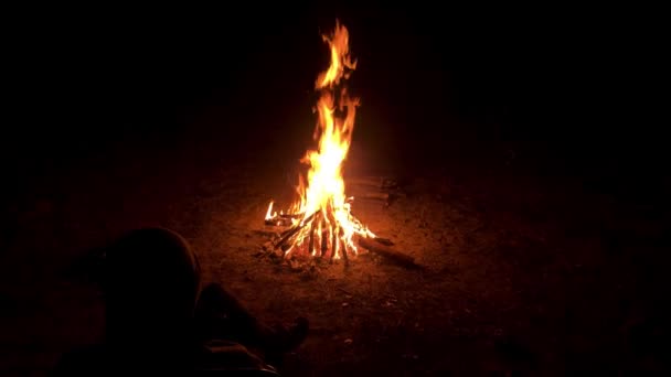 一个男人坐在一张扶手椅上，靠近夜晚海岸上明亮的火光 — 图库视频影像