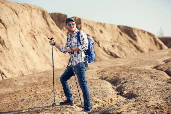 Foto van lachende toeristische man met wandelstokken op heuvel — Stockfoto