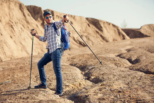 Foto eines lächelnden Touristenmannes, der Stöckchen zeigt, um auf einem Hügel vorwärts zu gehen — Stockfoto