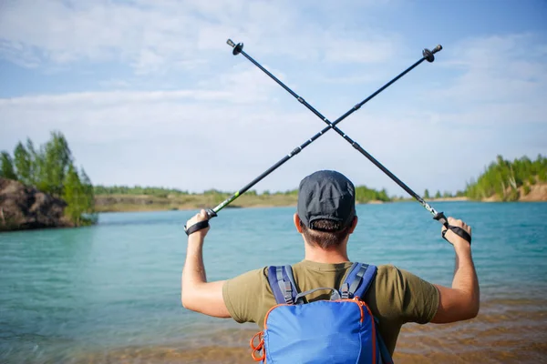 Photo from back of tourist man with crossed walking sticks on hill — Stock Photo, Image