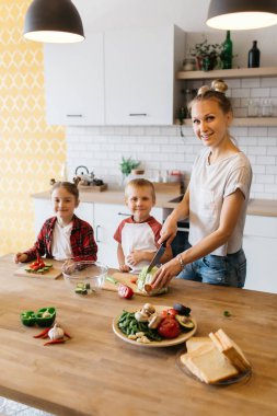 Genç Anne ile kızı ve oğlu kesme sebze masada fotoğrafı
